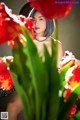 A woman sitting in front of a bunch of red flowers.