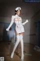 A woman in a white nurse outfit is posing for a picture.