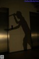 A silhouette of a man holding a baseball bat in an elevator.