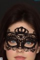 A woman wearing a black lace mask with a crown on it.