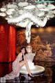 A woman sitting on a table in front of a chandelier.