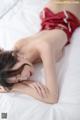 A woman in a red lingerie laying on a bed.