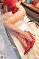 A woman in fishnet stockings and high heels sitting on a sink.