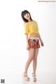 A woman in a yellow shirt and colorful shorts posing for a picture.