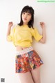 A woman in a yellow shirt and colorful skirt posing for a picture.