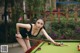 A woman in a black dress is playing pool.