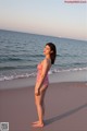 A woman in a pink bathing suit standing on a beach.