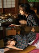 A woman laying on a bed eating food with chopsticks.