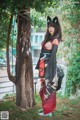 A woman in a kimono standing next to a tree.