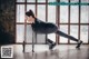 A woman doing push ups in front of a window.