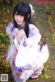 A woman in a kimono crouching down on the ground.