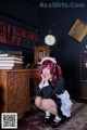 A woman in a maid outfit sitting on the floor in front of a desk.