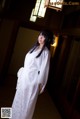 A woman in a white kimono standing in a room.