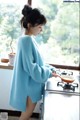 A woman in a blue sweater is cooking on a stove.