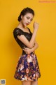 A woman in a black top and a floral skirt posing for a picture.