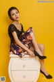 A woman sitting on top of a white dresser.