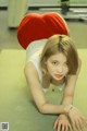 A woman laying on the floor with a red heart shaped pillow.