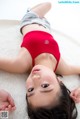 A young girl laying on a white rug with her hands on her head.