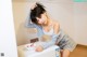 A woman leaning over a washing machine with a bowl of ice cream.