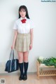 A woman in a school uniform holding a blue bag.