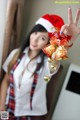 A woman in a santa hat holding up a bell.