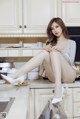 A woman sitting on top of a kitchen counter next to a stove.